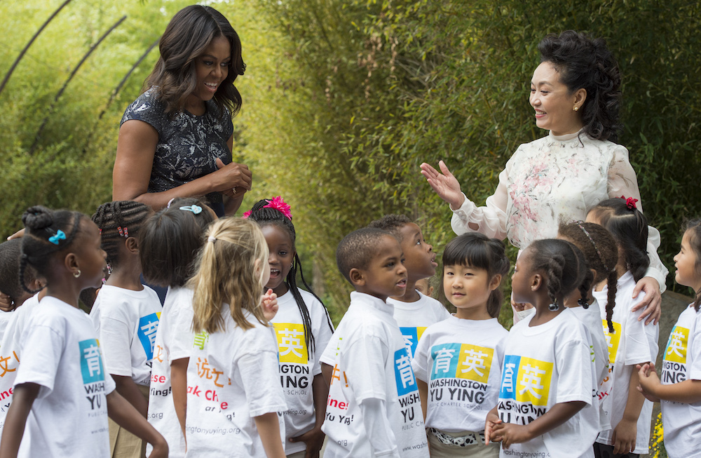 First Lady Michelle Obama and Madame Peng Liyuan, First Lady of the People's Republic of China, pose with students from Washington Yu Ying Public Charter School after their performance at the Smithsonian's National Zoo on September 25, 2015 in Washington, DC. AFP PHOTO/MOLLY RILEY